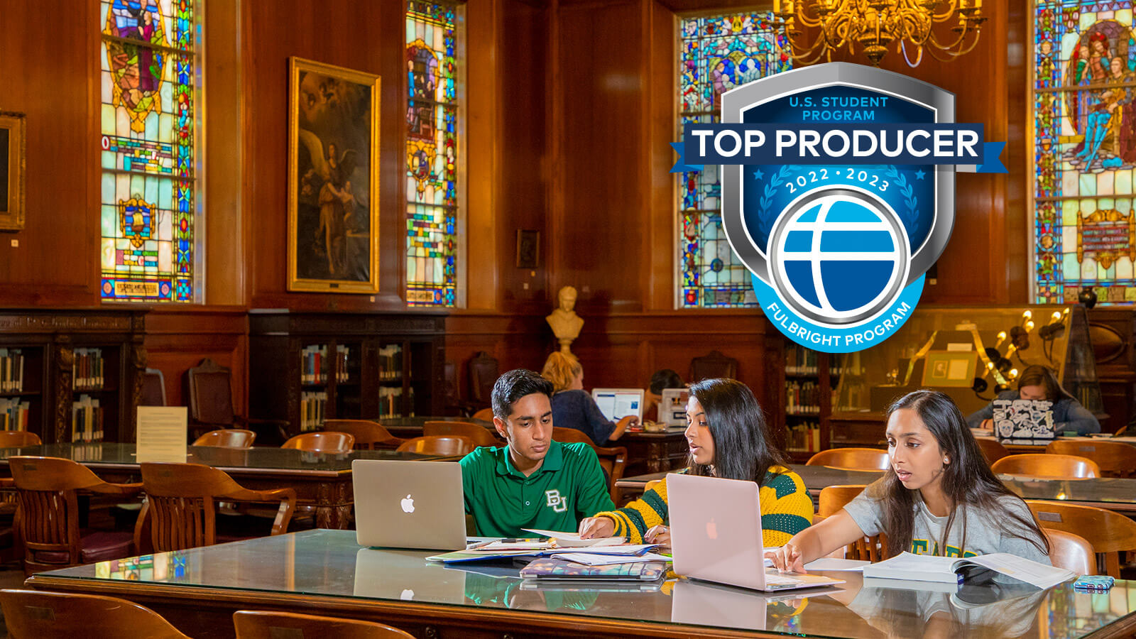 student working at laptops in the Armstrong Browning Library with Fulbright Top Producer badge above them