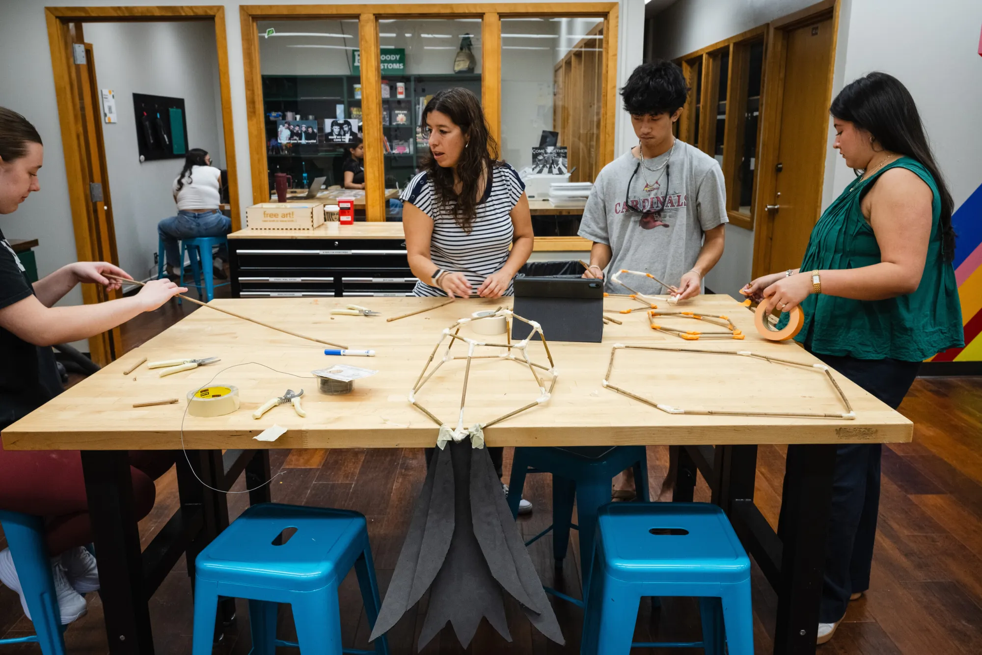 Professor Julie Cervantes with students constructing their Dia de Los Muertos parade puppet