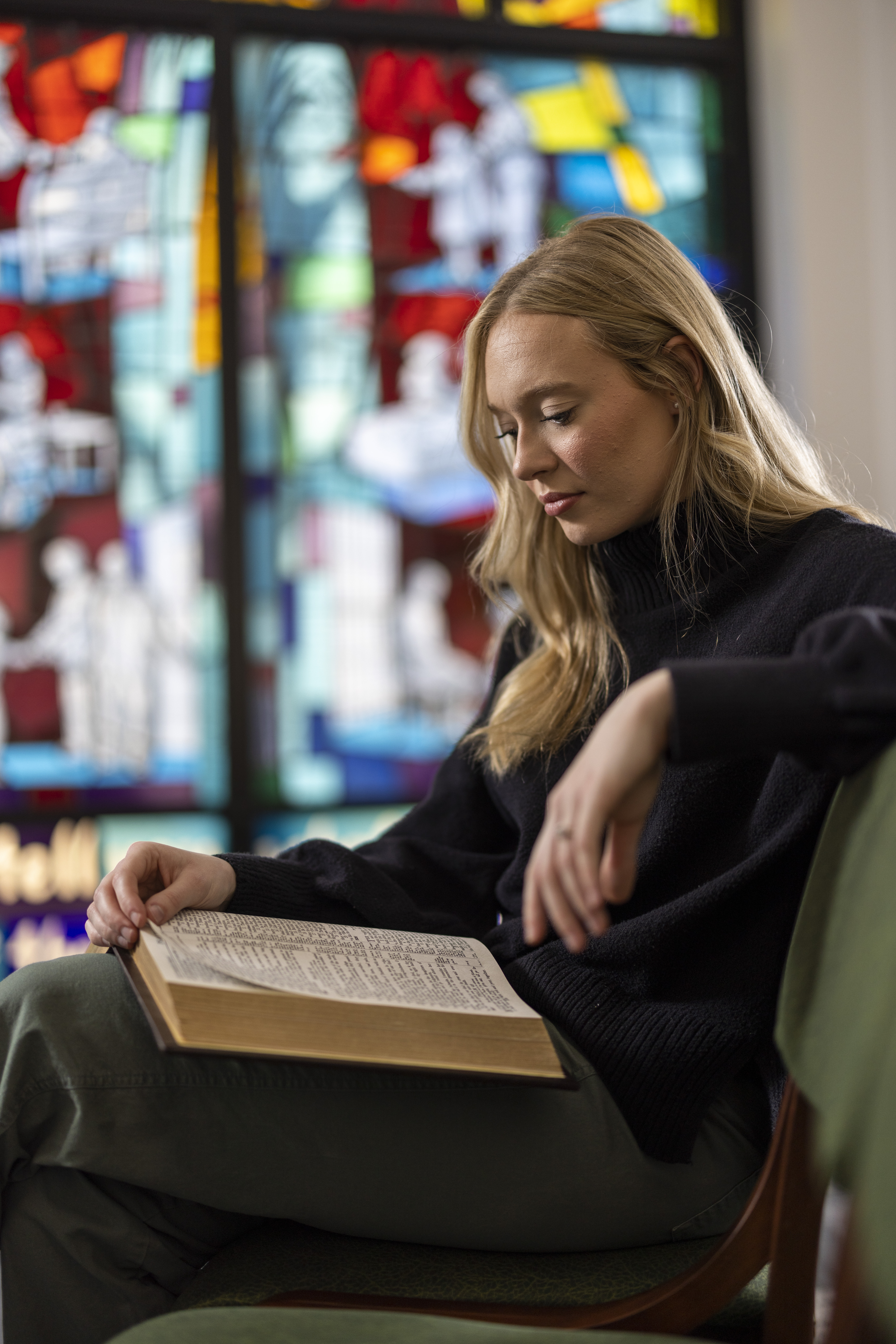 Person reading beside stained glass