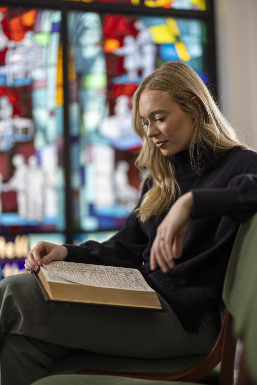 Person reading beside stained glass